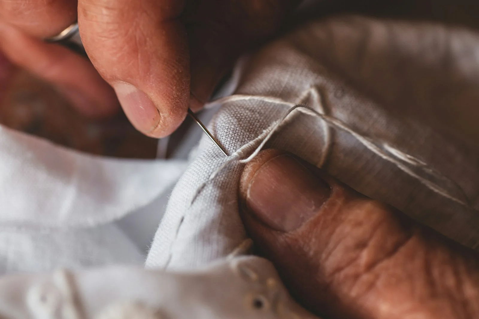 Mains réparant du tissu avec une aiguille et du fil